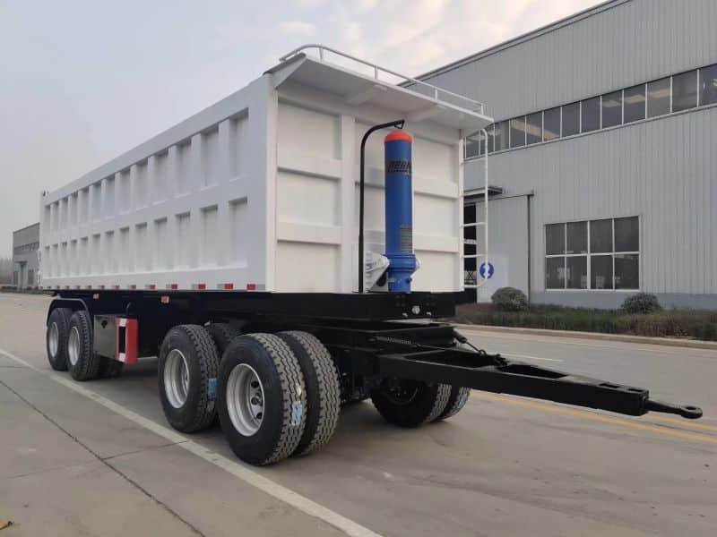 Two-axle dump trailer showcasing its hydraulic lift and high side walls.